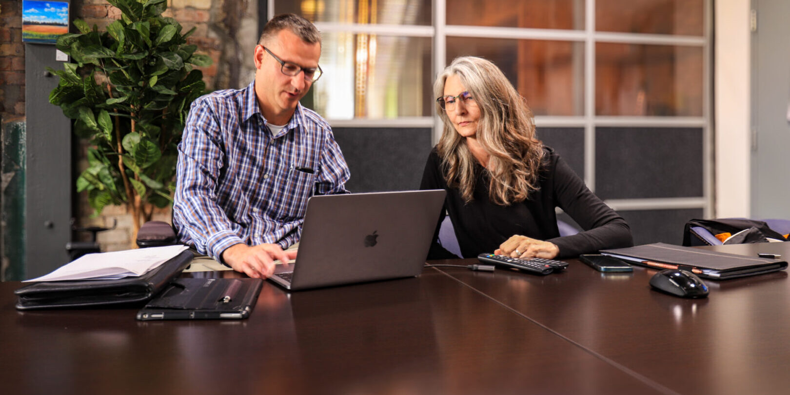 two business owners collaborating at a desk with laptop